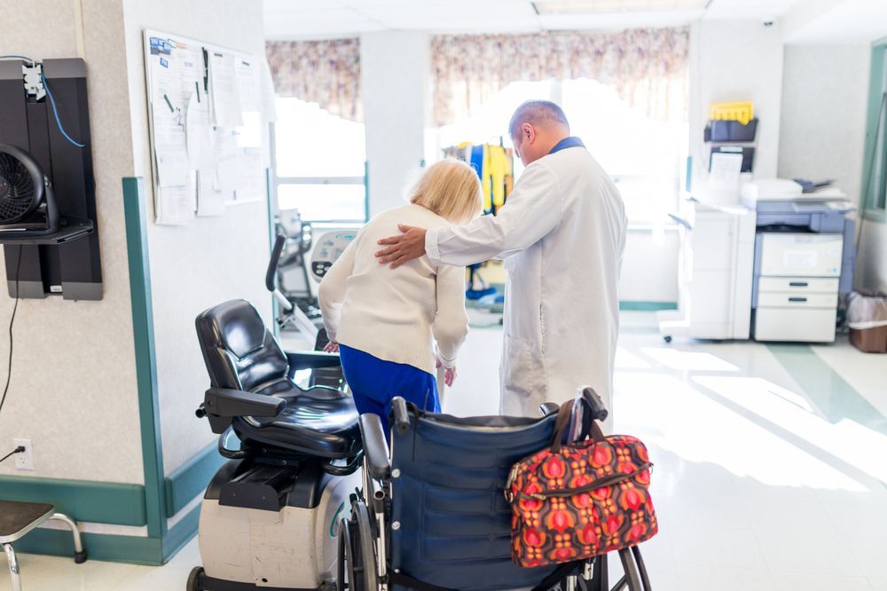 A doctor assisting a patient with mobility support in a hospital setting.