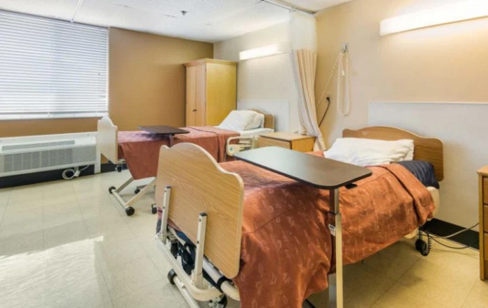 An empty hospital room with two patient beds and medical equipment.