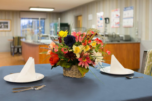 A beautifully arranged floral centerpiece on a dining table, accompanied by neatly folded napkins and cutlery.
