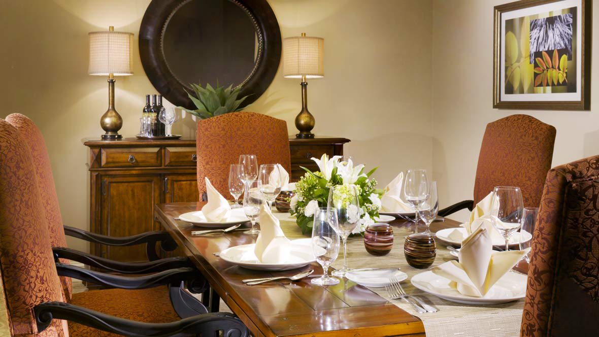 A beautifully set dining table with elegant tableware and a floral centerpiece.