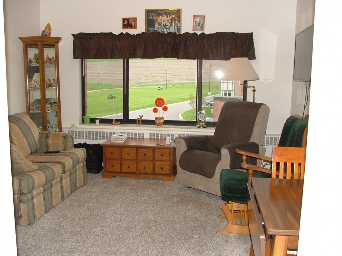 A cozy living room with a sofa, chairs, and a large window overlooking the outdoors.