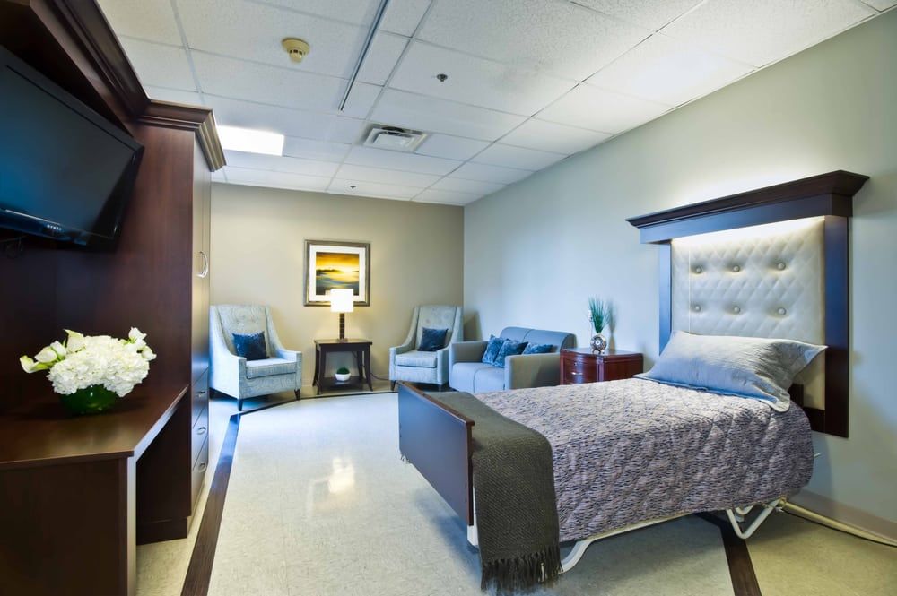 A modern hospital room with a comfortable bed, seating area, and clean design.