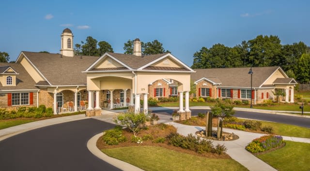 A well-maintained residential building with landscaped gardens and a driveway.