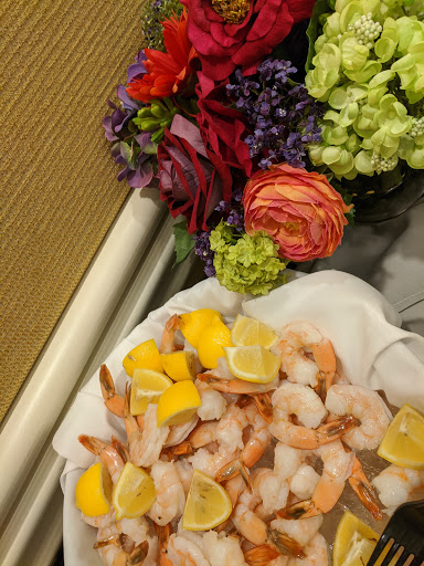 A beautifully arranged platter of shrimp served with lemon slices, accompanied by a vibrant floral display.