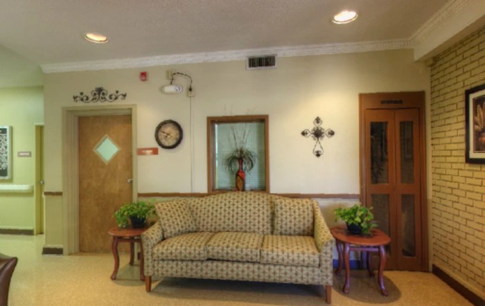 A cozy lobby area featuring a patterned sofa, decorative plants, and wall art.