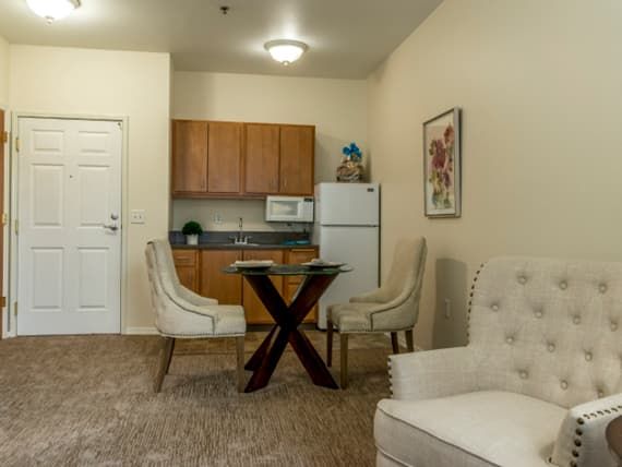 A cozy kitchenette and dining area in an apartment, featuring modern chairs, a table, and essential kitchen appliances.