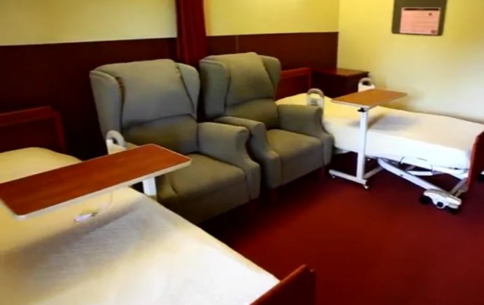 A hospital room with comfortable chairs and medical beds arranged for patient care.