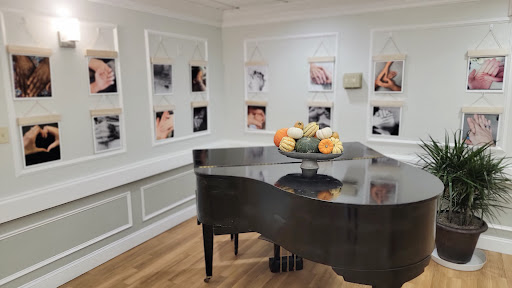 A stylish interior featuring a grand piano and artistic photographs on the walls.