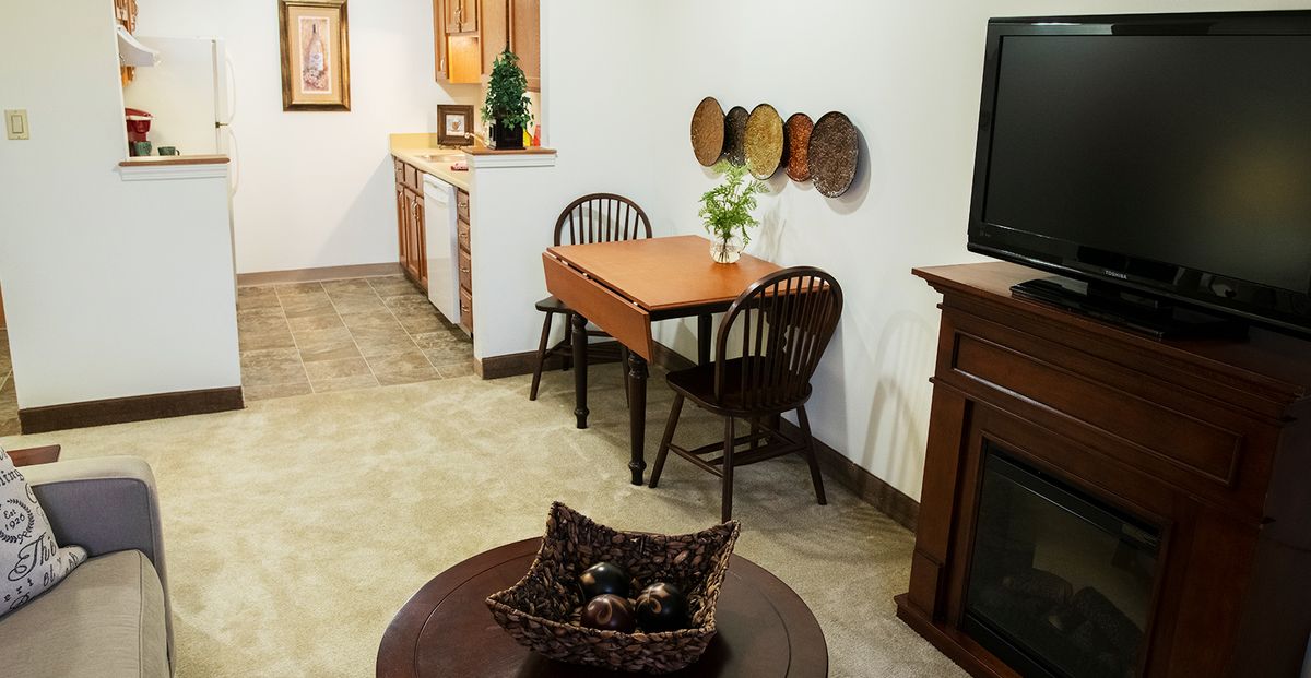 A cozy dining area with a wooden table and chairs, decorated with wall plates and a vase centerpiece.