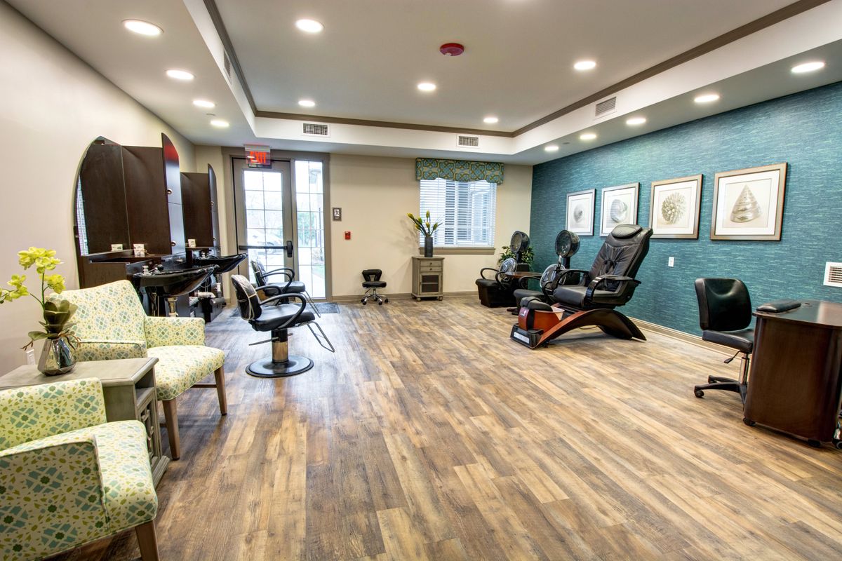 A well-lit salon interior featuring comfortable chairs and a wooden floor.