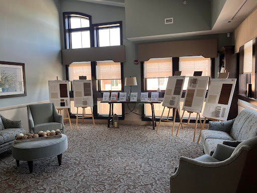 A spacious interior featuring an art exhibition with several display boards, surrounded by comfortable seating.