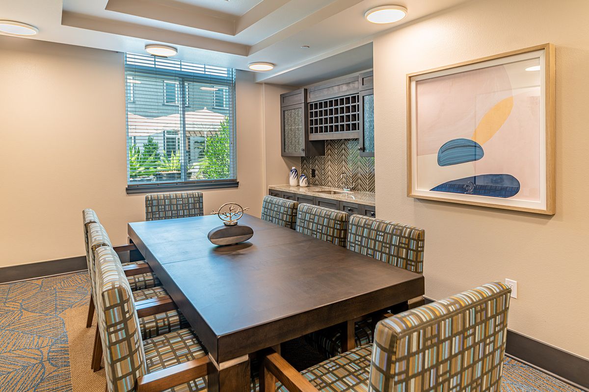 A modern dining area with a large table, upholstered chairs, and abstract artwork on the wall.