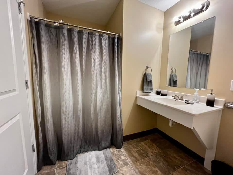 A modern bathroom with a shower curtain and a well-lit vanity area.