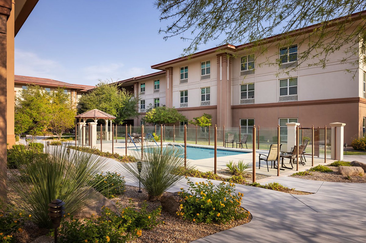 A modern apartment complex with an outdoor pool and landscaped surroundings.