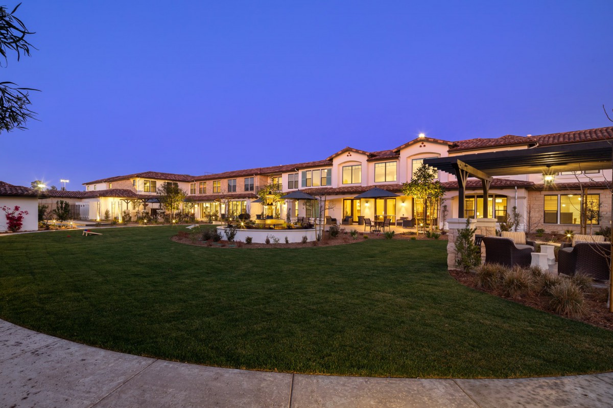 A beautifully lit building exterior at dusk with a well-maintained lawn.