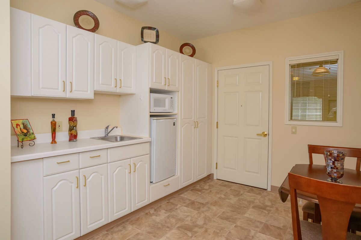 A small, neatly organized kitchen with white cabinets and a tiled floor.