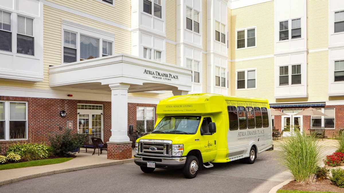 A bright yellow shuttle bus parked in front of a hospital building.