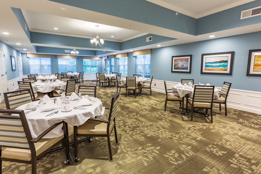 A well-arranged dining room with tables and chairs neatly set up, featuring elegant interior design and carpeted flooring.