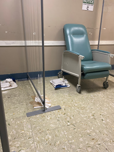A view of a hospital patient area featuring a green chair and some medical equipment on the floor.