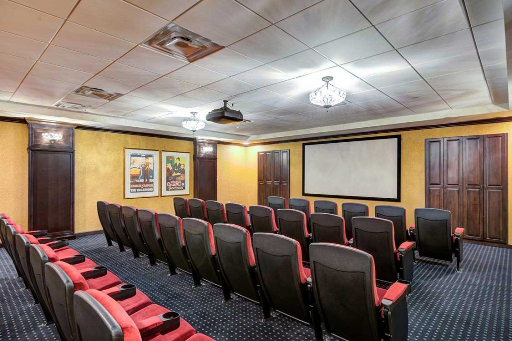 Small private theater room with rows of red and black seats facing a large screen.