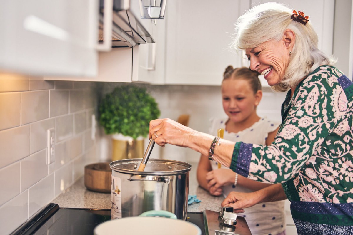 A grandmother and her grandchild enjoy cooking together in the kitchen.