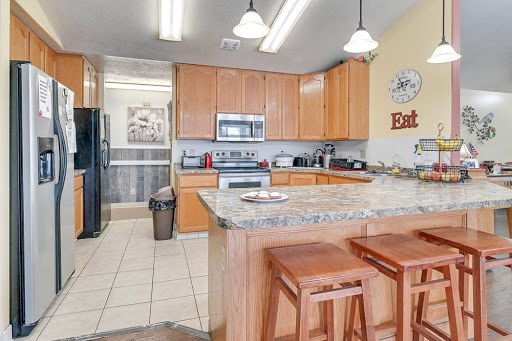 A modern kitchen featuring wooden cabinets and a granite countertop, equipped with essential appliances.