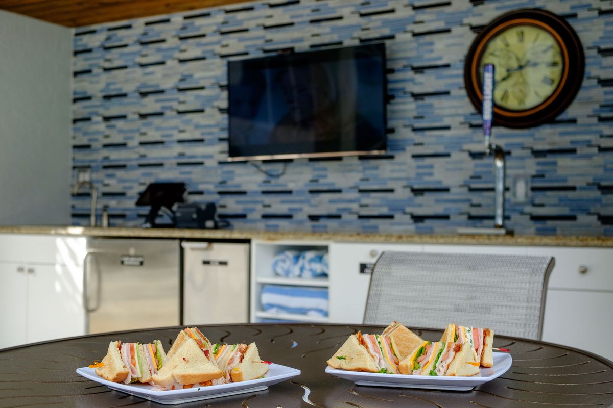 Plates of sandwiches on a table in a modern kitchen setting.