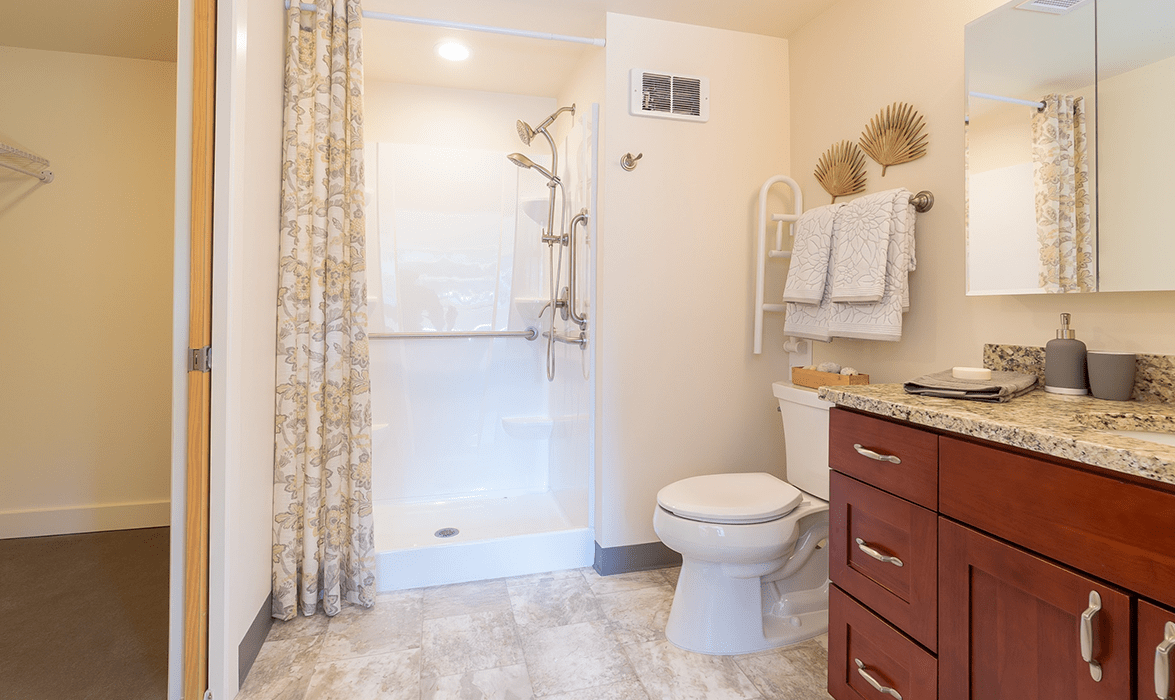 A clean and modern bathroom with a shower, toilet, and neatly arranged towels.