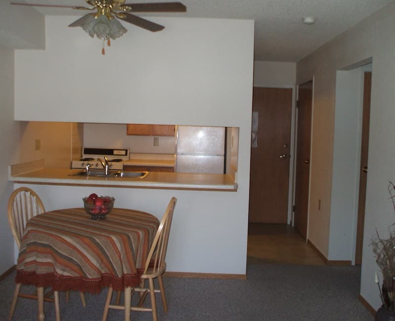 A cozy dining area adjacent to a small kitchen with wooden cabinetry.