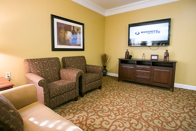 A cozy living room with armchairs, a television, and warm decor.