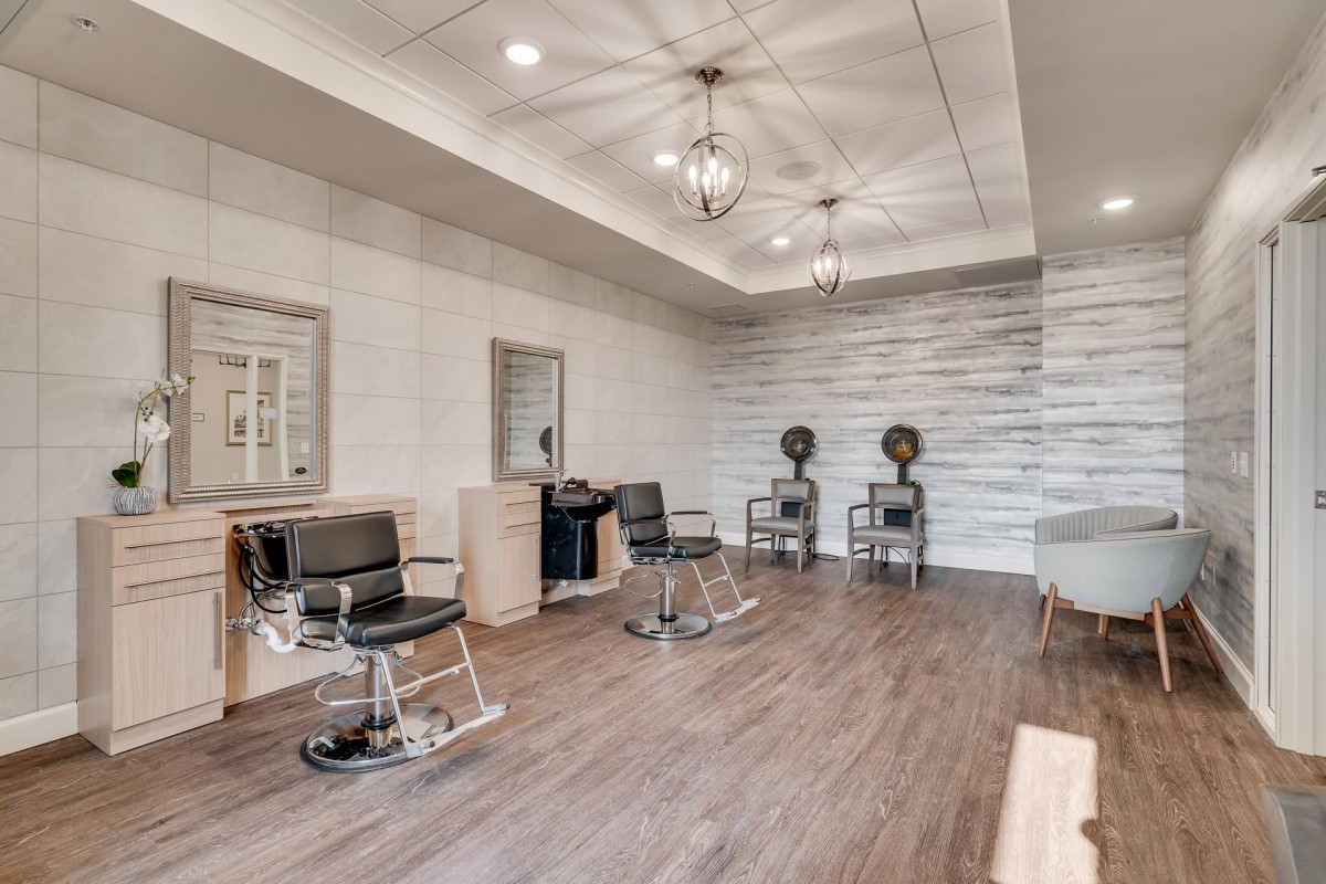 A modern salon interior with styling chairs, mirrors, and hair dryers on a wooden floor.
