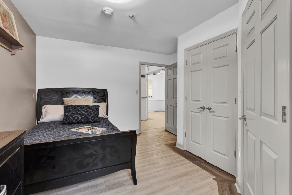 A modern bedroom with a black bed, decorative pillows, and light wood flooring.