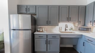 A modern kitchen with gray cabinets and stainless steel appliances.