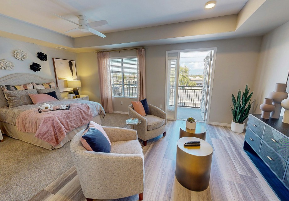 A stylish modern bedroom with cozy seating, elegant decor, and access to a balcony.