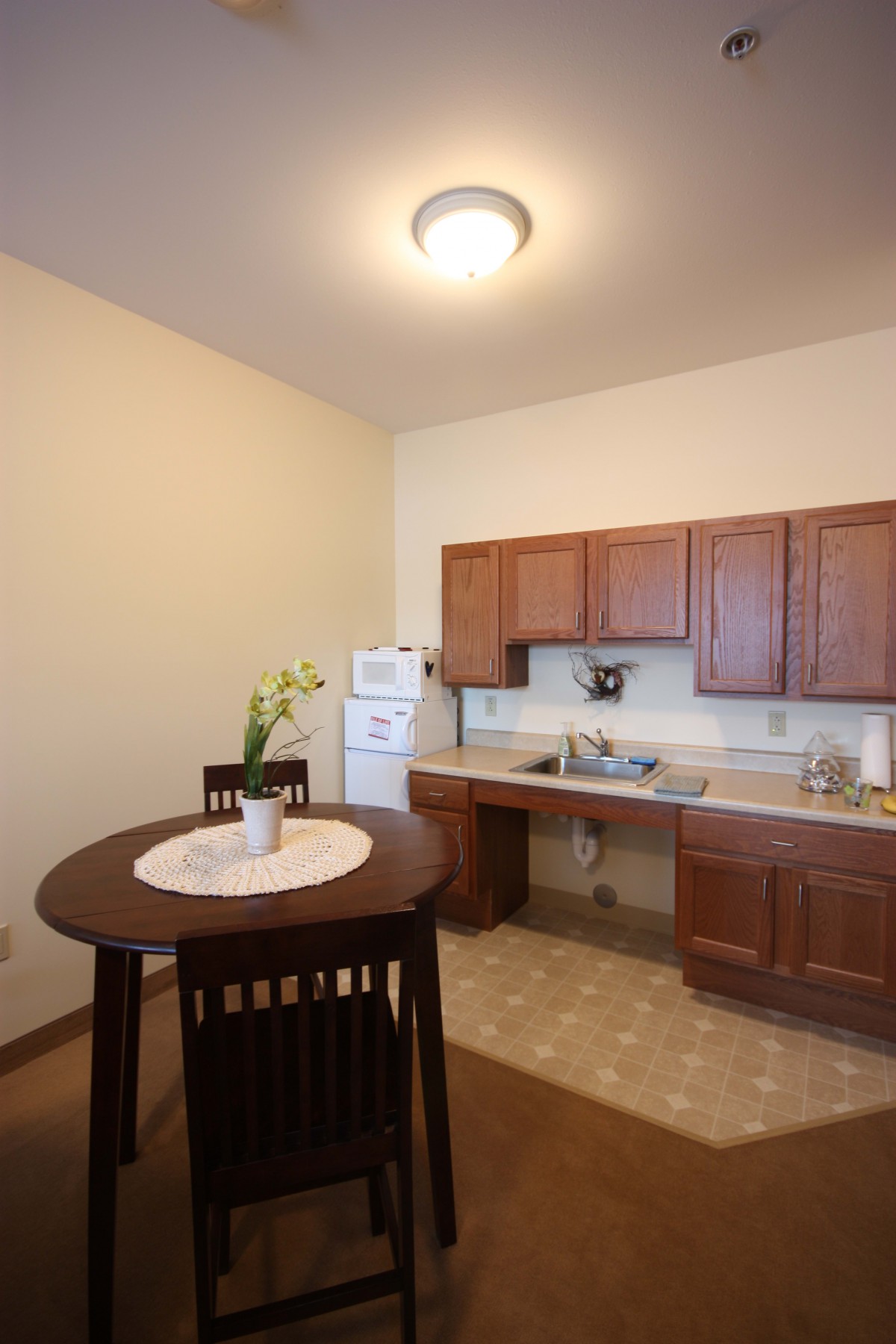 A small kitchen area with a round dining table, chairs, and wooden cabinets.