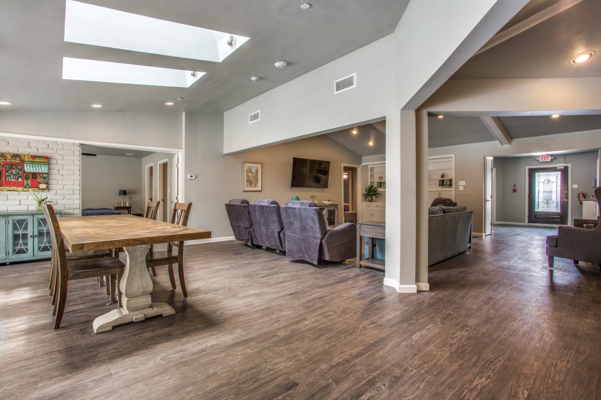 A spacious open-concept living and dining area with wood flooring and skylights.