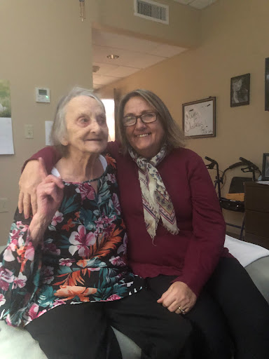 A heartwarming moment shared between a caregiver and an elderly woman, both smiling and enjoying each other's company.