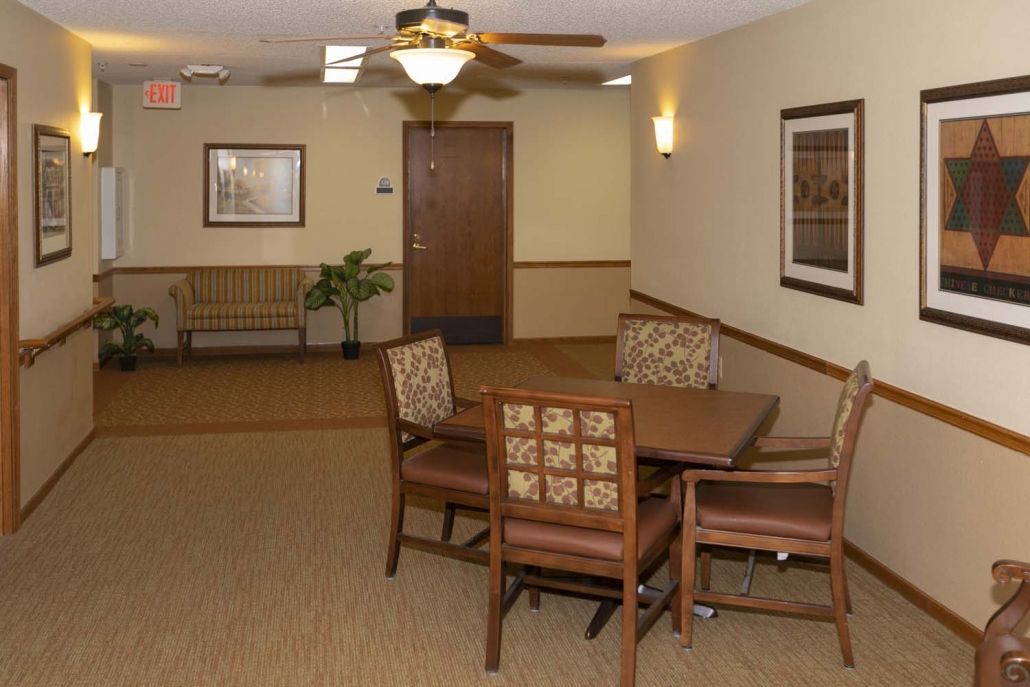A cozy lobby area featuring a table with chairs, wall art, and soft lighting.