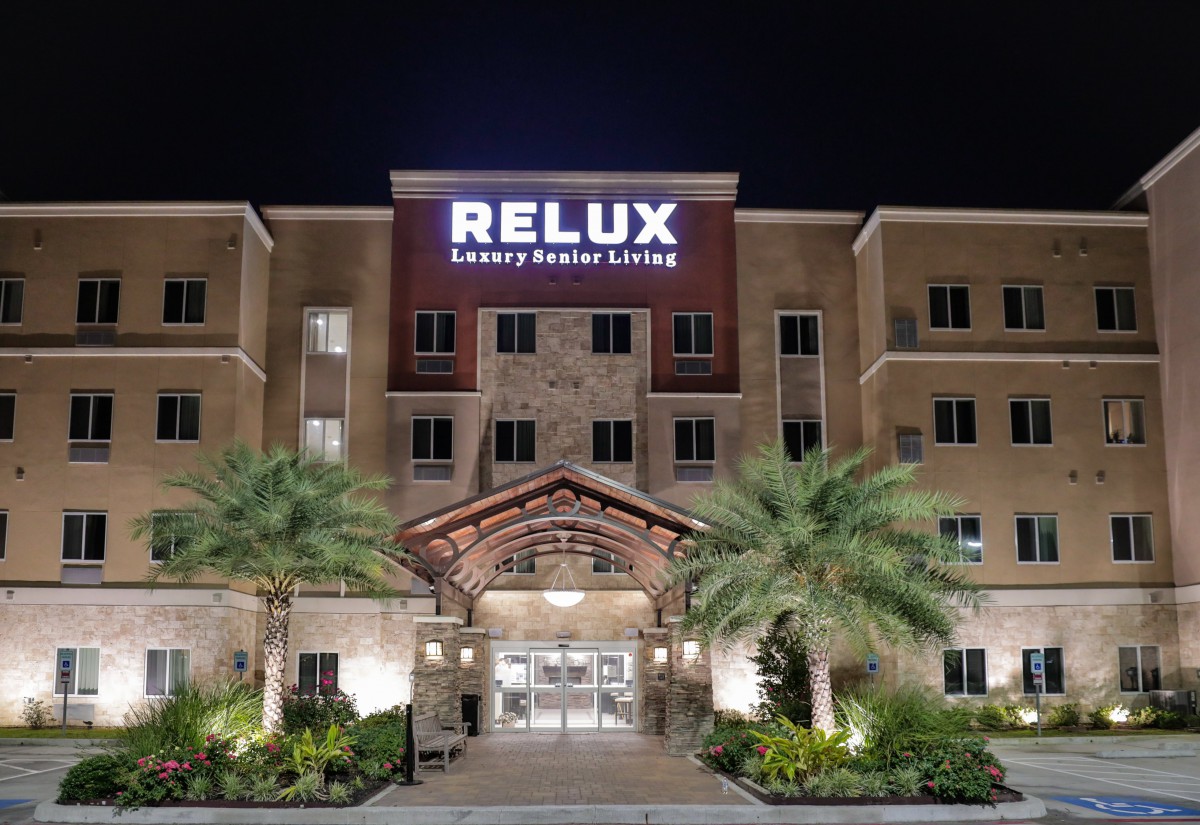 The illuminated entrance of Relux Luxury Resort at night, surrounded by palm trees.