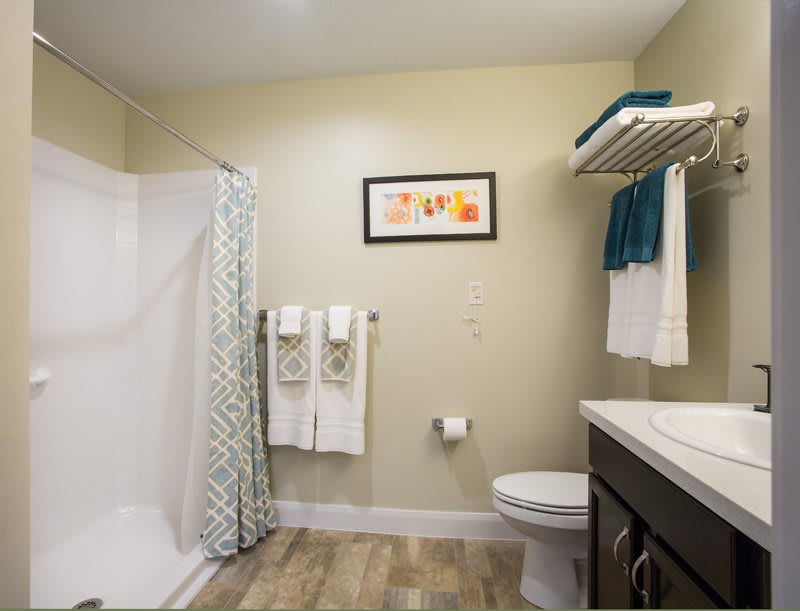 A modern bathroom with a spacious shower, neatly arranged towels, and elegant decor.