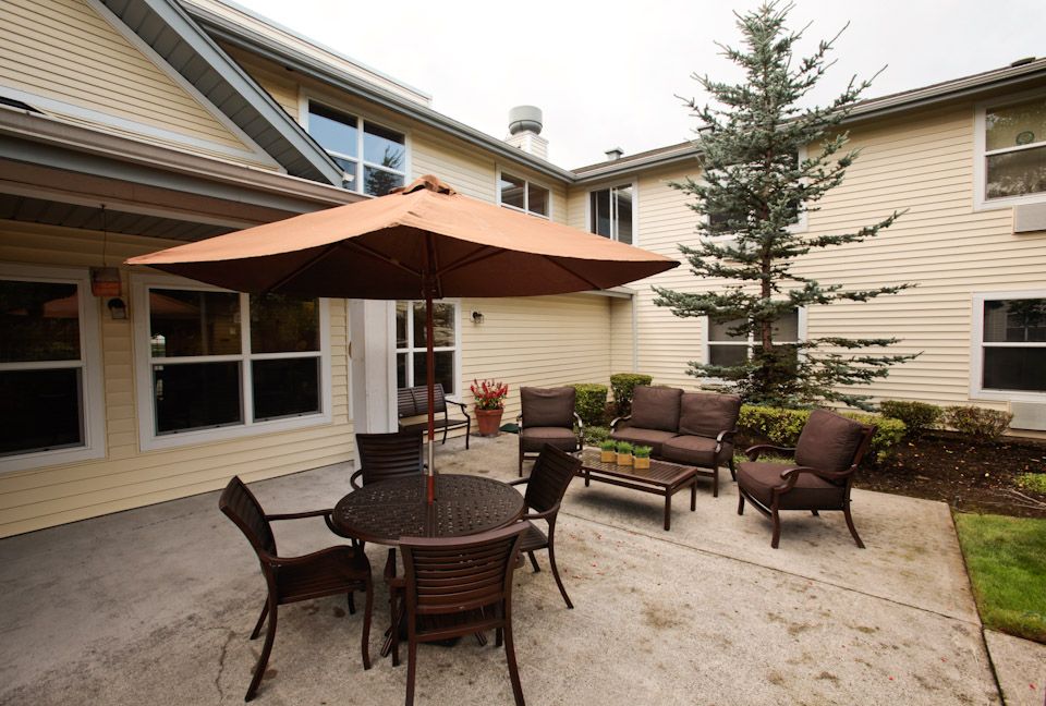 A cozy patio area with an umbrella-shaded table and comfortable chairs.