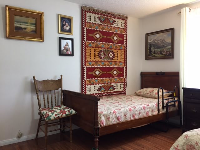 A cozy bedroom featuring a wooden bed, decorative tapestry, and vintage wall art.