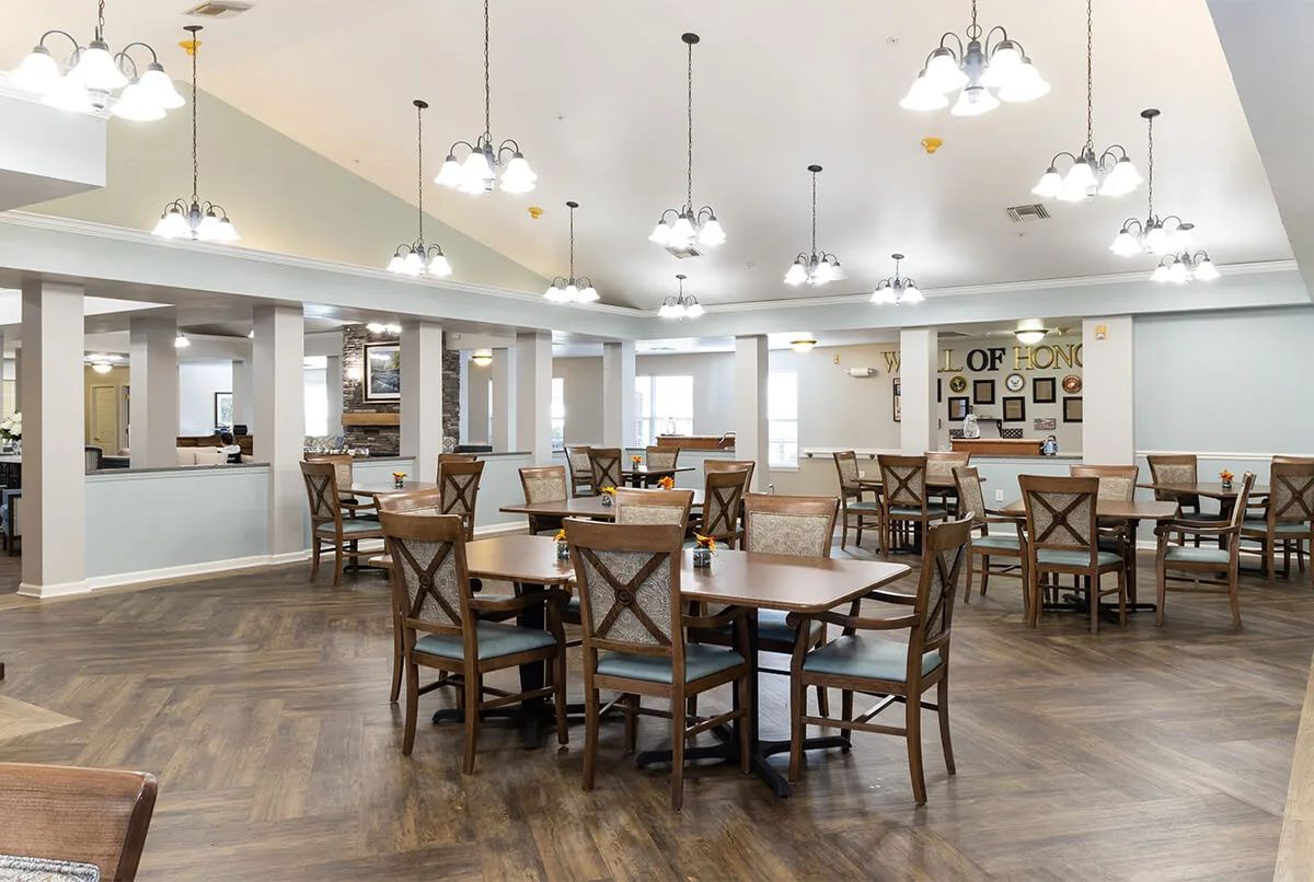 A spacious and well-lit dining area with wooden tables and chairs, featuring elegant lighting fixtures.