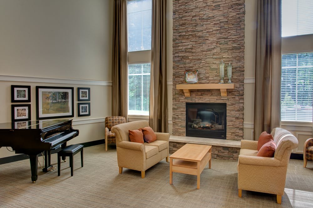 A cozy living room with modern furniture, featuring a piano and a fireplace.