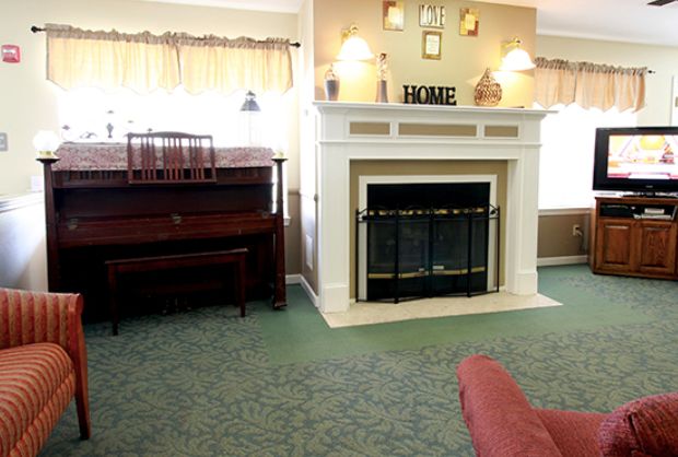 A cozy living room featuring a fireplace and a piano, with soft lighting and homey decor.