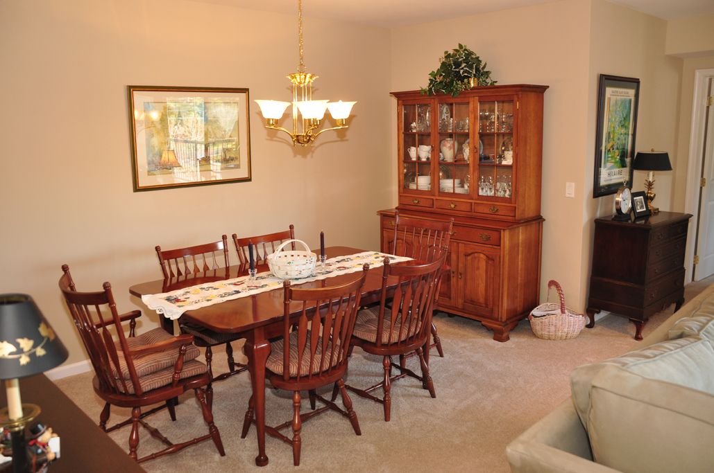 A cozy dining room with a wooden table and chairs, accompanied by a matching china cabinet and an elegant chandelier.