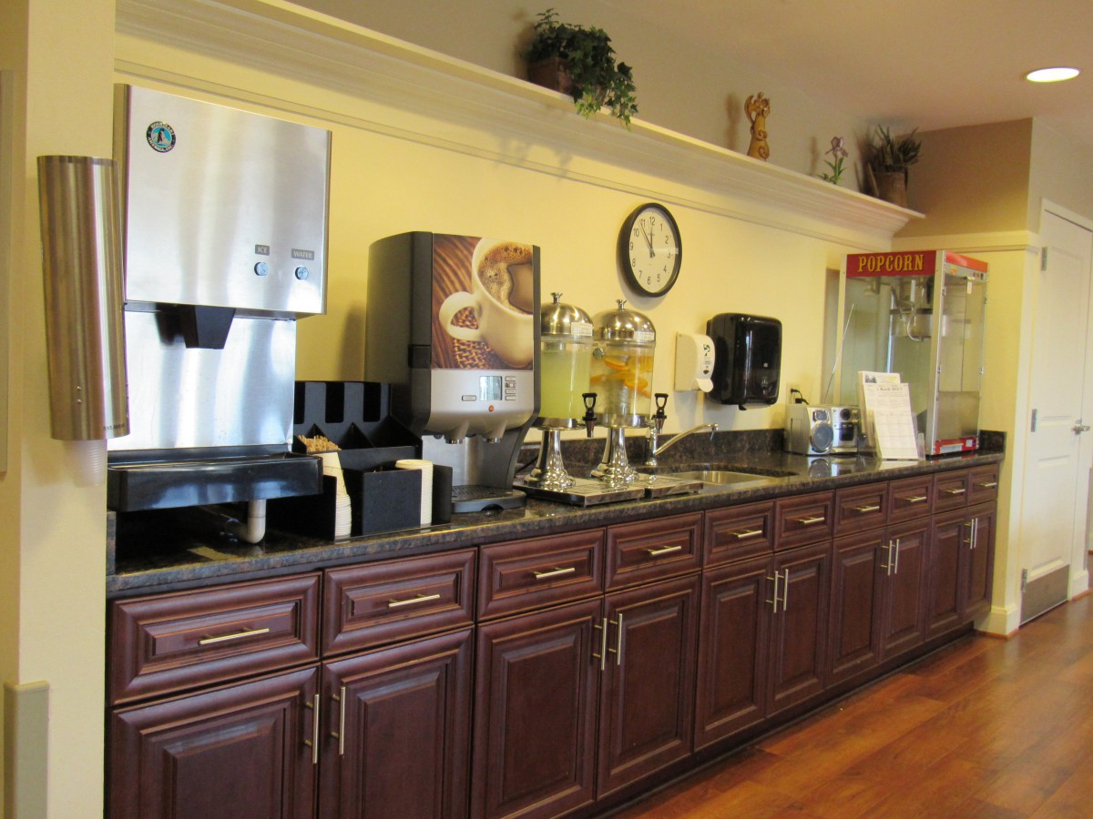A well-equipped hotel breakfast area featuring a coffee machine, juice dispensers, and other beverage options.