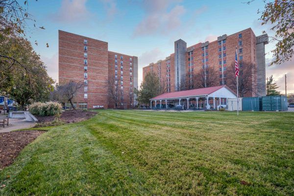 A view of apartment buildings with a large grassy lawn in the foreground.