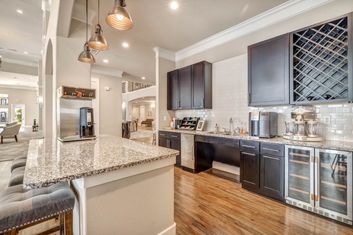 A modern kitchen with dark cabinets, granite countertops, and pendant lighting.