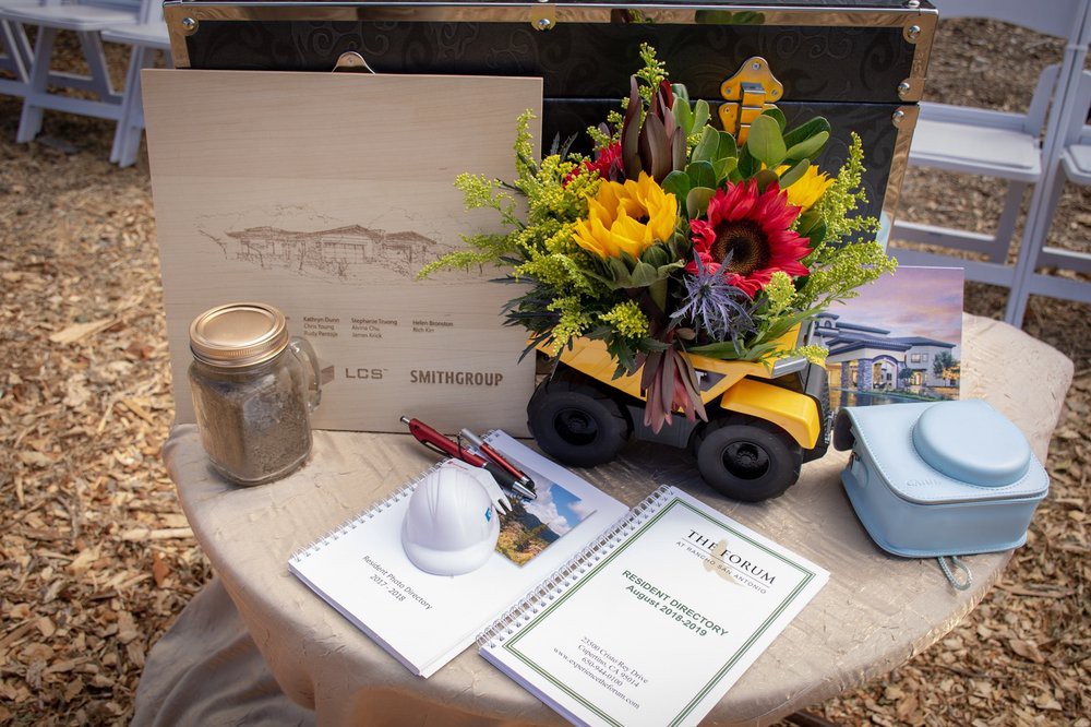 A construction-themed table setting featuring a toy truck filled with vibrant flowers, a hard hat, and various stationery items.